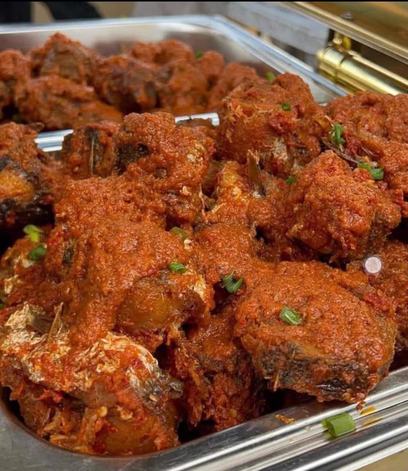 A chafing dish of rich tomato stew with assorted meat and fish