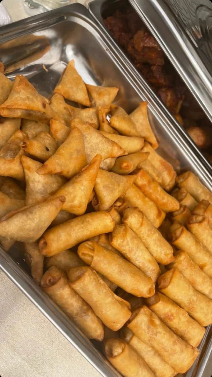 A service tray of golden samosas and spring rolls ready for guests