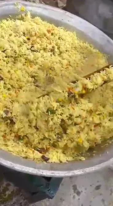 In the kitchen — Rice turned by hand in a catering pot during preparation for an event order.